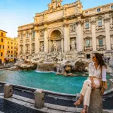 Donna seduta vicino alla Fontana di Trevi, un'icona di Roma. Perfetto per chi cerca dove dormire a Roma e vivere la magia della città eterna.