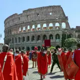 Rievocazione storica del Natale di Roma con legionari in armatura davanti al Colosseo.