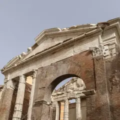 Antica struttura in mattoni e marmo, con colonne e un arco, parte del **Portico di Ottavia**.
