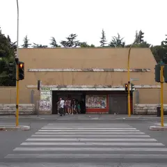 Ingresso della metro Cornelia a Roma, con persone in attesa e semafori rossi.