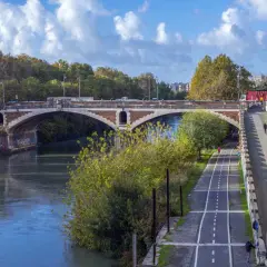 Il ponte nuovo di Roma attraversa il Tevere, con una pista ciclabile e pedonale lungo la riva.