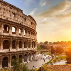 Il Colosseo al tramonto, con il suo clima mite, accoglie visitatori sotto un cielo dorato.