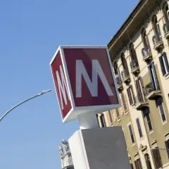 Segnale della metro con la "M" rossa su sfondo bianco, vicino a un palazzo storico. Baldo degli Ubaldi metro.