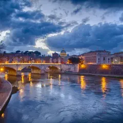 Il Tevere riflette le luci di Roma al tramonto, un'atmosfera magica per decidere cosa fare il sabato sera a Roma.