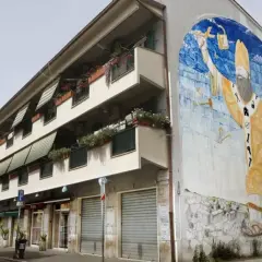 San Basilio, Roma: un imponente murale raffigurante San Basilio con simboli di protezione e cura, adorna un edificio residenziale.