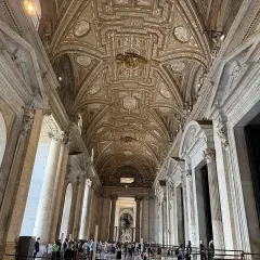 Interno della chiesa di San Pietro a Roma, con soffitto a cassettoni dorato e colonne imponenti.