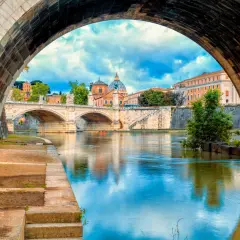 Ponte Sant'Angelo e il Tevere, un'icona di cosa vedere a Roma. La cupola di San Pietro si riflette sull'acqua.