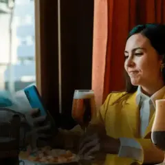 Donna con smartphone e bicchieri di birra. Scopri come si può comprare il birg online per gustarlo comodamente.