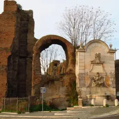 Antica porta furba metro, con fontana e rovine romane.