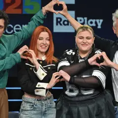 Artisti sorridono formando cuori con le mani, pronti per il concerto Roma 1 Maggio.