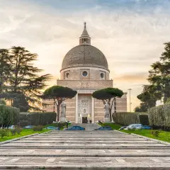 La Basilica dei Santi Pietro e Paolo a Roma, con la sua imponente cupola, si erge maestosa tra alberi secolari e giardini curati.