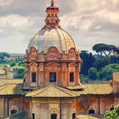 Cupola della chiesa dei Santi Luca e Martina a Roma, con tetti e alberi circostanti sotto un cielo nuvoloso.