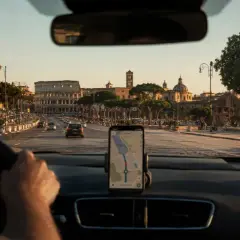 Navigatore in auto indica la strada per la stazione metro Anagnina, con il Colosseo sullo sfondo.