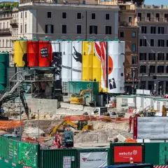 Cantiere per i lavori metro Roma con grandi teli colorati e macchinari edili.