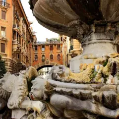 Fontana barocca a Roma Nord, con palazzi storici sullo sfondo e acqua che scorre tra le sculture.