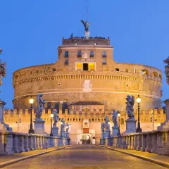 Ponte Sant'Angelo illuminato di sera, con le statue degli angeli e Castel Sant'Angelo sullo sfondo. Curiosità: la statua in cima al castello.