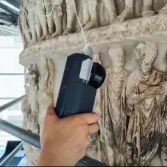 Tecnico con visore AR esamina i rilievi della Colonna di Marco Aurelio, creando un riassunto digitale della sua storia.