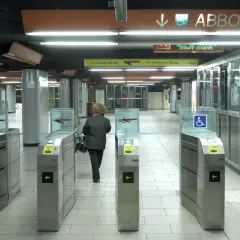 Ingresso della metropolitana di Roma con tornelli ATAC. Una donna attraversa i varchi per accedere ai binari.