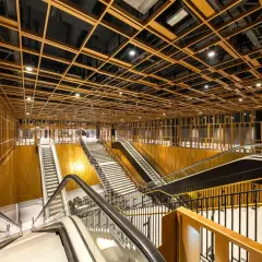 Interni moderni di una stazione metro con soffitto a griglia dorata, scale mobili e gradinate. Un assaggio delle future metro c fermate.