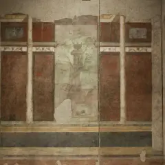 Affresco nella casa di Livia: colonne, pannelli rossi e un paesaggio centrale con un albero e un vaso.