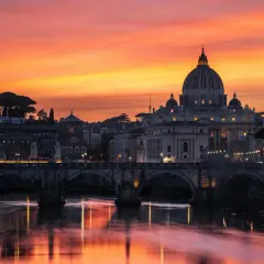 Tramonto infuocato su Roma, con San Pietro e Ponte Sant'Angelo. Un'immagine iconica della città eterna, perfetta per la alta stagione Roma.