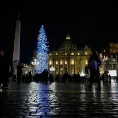 Piazza San Pietro illuminata da un grande albero di Natale blu, con gente che passeggia. Un'idea su cosa fare il 24 dicembre a Roma.