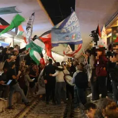 Folla in piazza a Roma per uno sciopero venerdì, sventolano bandiere palestinesi e altri vessilli.