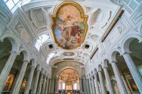 Interno della Basilica di San Pietro, con affreschi sul soffitto e colonne imponenti.