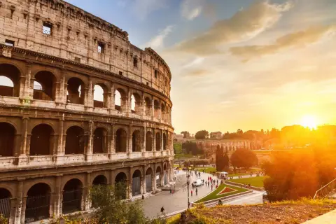 Il Colosseo al tramonto, con il suo clima mite, accoglie visitatori sotto un cielo dorato.