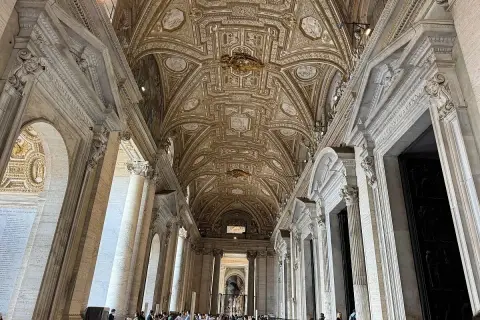 Interno della chiesa di San Pietro a Roma, con soffitto a cassettoni dorato e colonne imponenti.