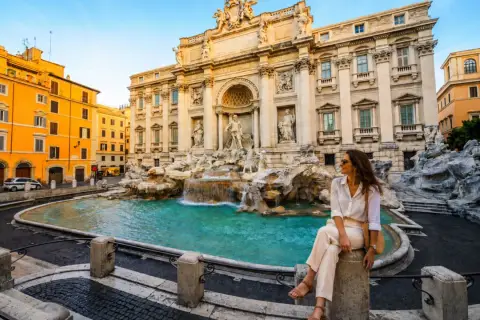 Donna seduta vicino alla Fontana di Trevi, un'icona di Roma. Perfetto per chi cerca dove dormire a Roma e vivere la magia della città eterna.