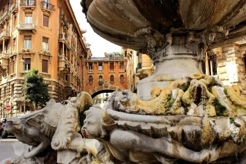 Fontana barocca a Roma Nord, con palazzi storici sullo sfondo e acqua che scorre tra le sculture.