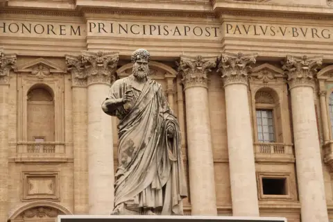 Statua di San Pietro davanti alla Basilica. La scritta "IN HONOREM PRINCIPIS APOST PAVLSV-BVRGHESIVS" celebra i santi Pietro e Paolo.