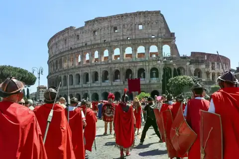 Rievocazione storica del Natale di Roma con legionari in armatura davanti al Colosseo.