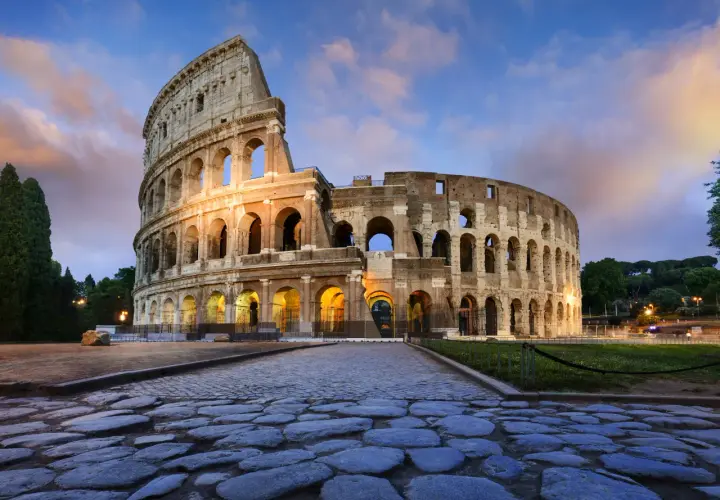 Il Colosseo, uno dei più maestosi monumenti di Roma, illuminato al tramonto con un cielo suggestivo.