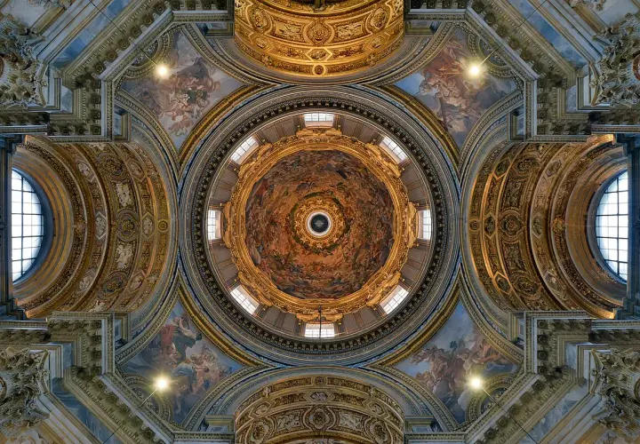 Soffitto affrescato di una delle magnifiche chiese barocche di Roma, con cupola centrale e decorazioni dorate.