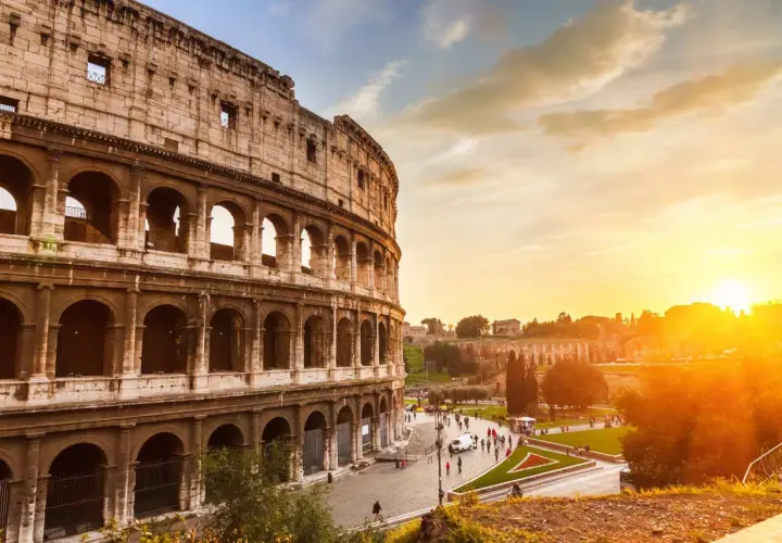 Il Colosseo al tramonto, con il suo clima mite, accoglie visitatori sotto un cielo dorato.