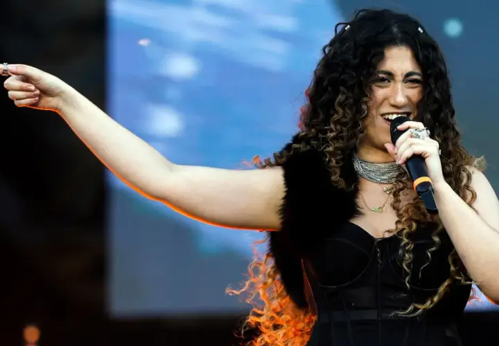 Una delle tanti artisti primo maggio, canta con passione sul palco, indicando il pubblico con un gesto energico.