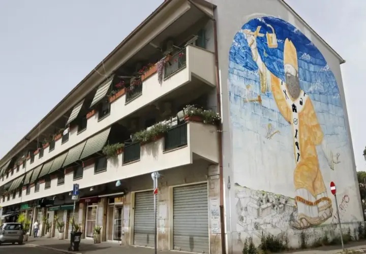 San Basilio, Roma: un imponente murale raffigurante San Basilio con simboli di protezione e cura, adorna un edificio residenziale.