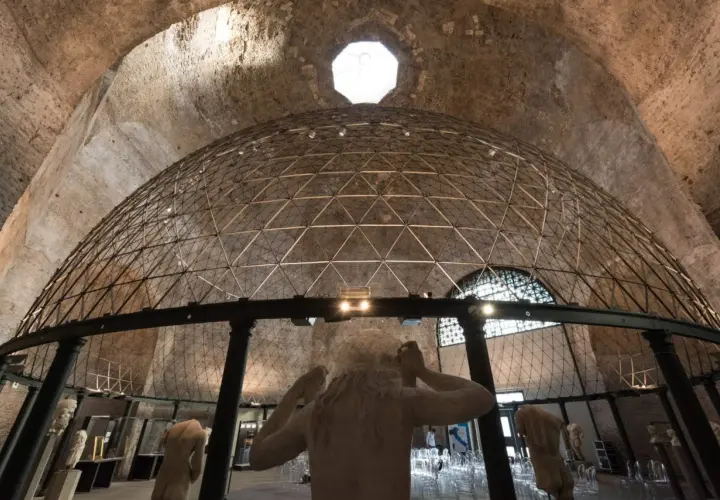 Interno di un'aula ottagona con cupola geodetica e sculture antiche. Luce zenitale illumina l'ambiente.