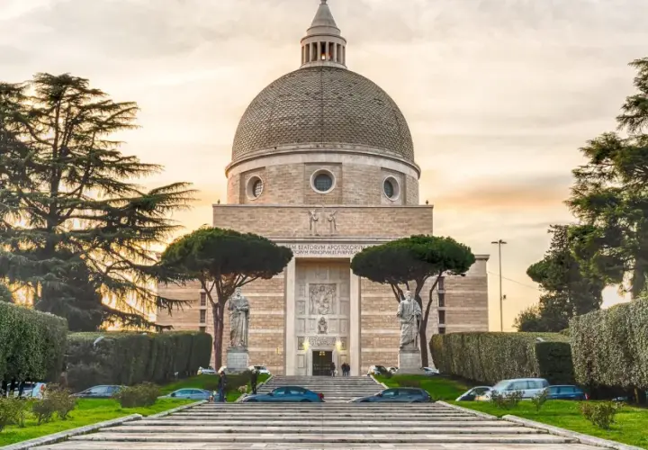 Basilica di San Pietro e Paolo a Roma, con la sua imponente cupola e statue, circondata da alberi e giardini curati.