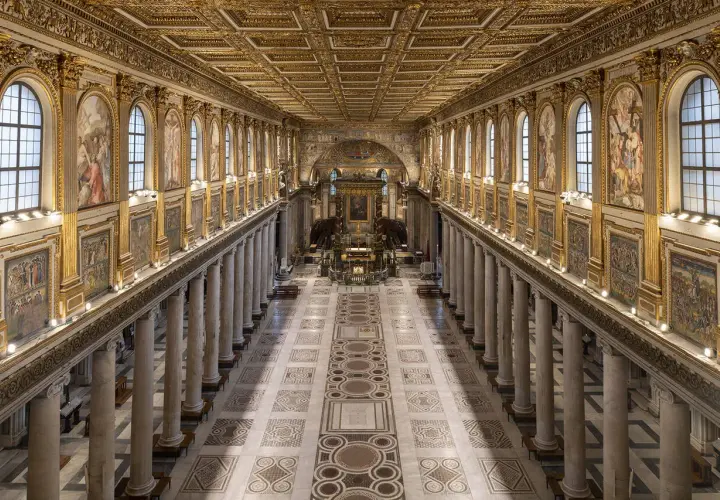 L'interno della Basilica di Santa Maria Maggiore a Roma, con il suo soffitto dorato, le colonne imponenti e i mosaici che narrano storie sacre.