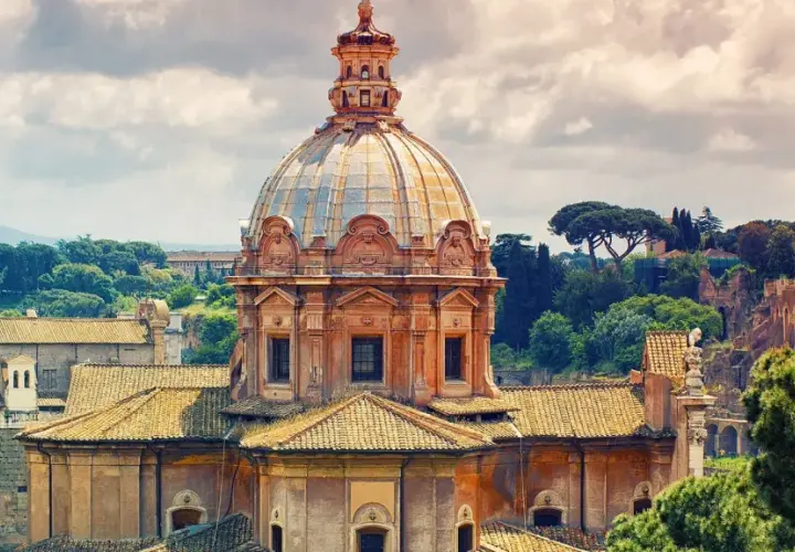 Cupola della chiesa dei Santi Luca e Martina a Roma, con tetti e alberi circostanti sotto un cielo nuvoloso.