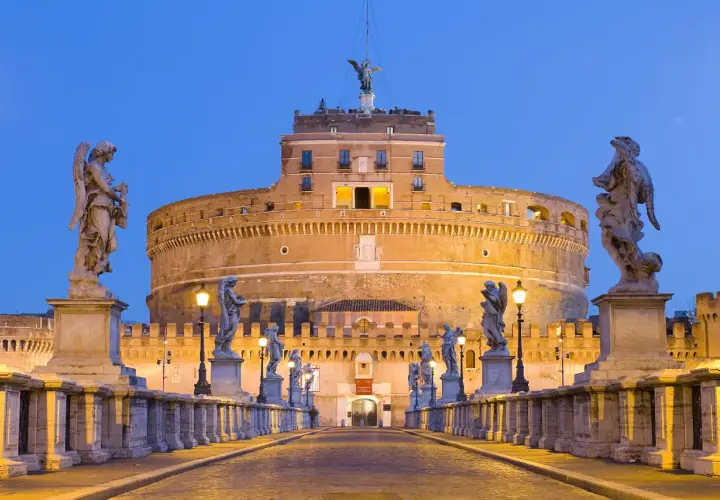 Ponte Sant'Angelo illuminato di sera, con le statue degli angeli e Castel Sant'Angelo sullo sfondo. Curiosità: la statua in cima al castello.