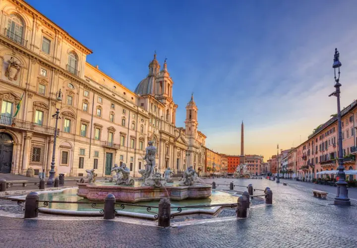Fontana dei Quattro Fiumi e il palazzo prospiciente in Piazza Navona, Roma, al tramonto.