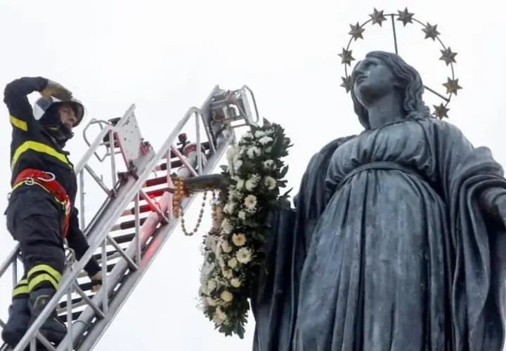 Vigile del fuoco su scala decora la statua della Madonna con fiori per l'8 dicembre a Roma.