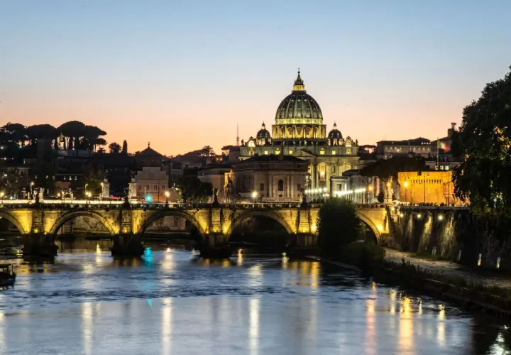 Ponte Sant'Angelo illuminato al tramonto, con Castel Sant'Angelo e la cupola di San Pietro. Un'idea su cosa fare il pomeriggio a Roma.