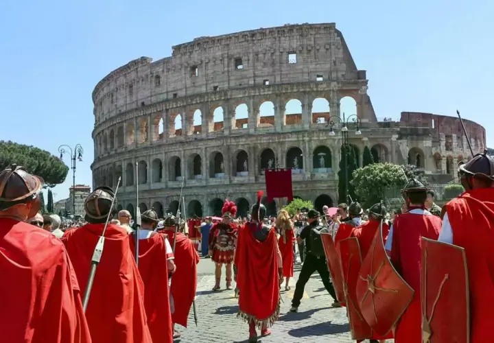 Rievocazione storica del Natale di Roma con legionari in armatura davanti al Colosseo.