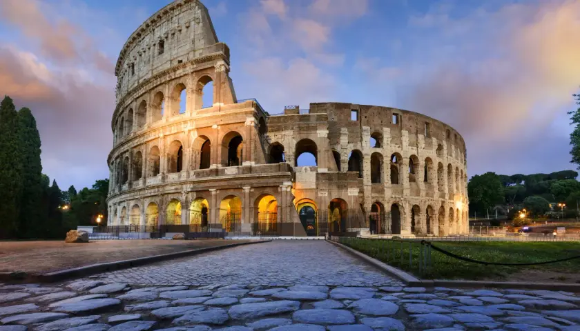 Il Colosseo, uno dei più maestosi monumenti di Roma, illuminato al tramonto con un cielo suggestivo.