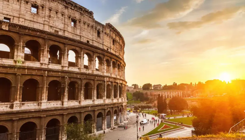 Il Colosseo al tramonto, con il suo clima mite, accoglie visitatori sotto un cielo dorato.